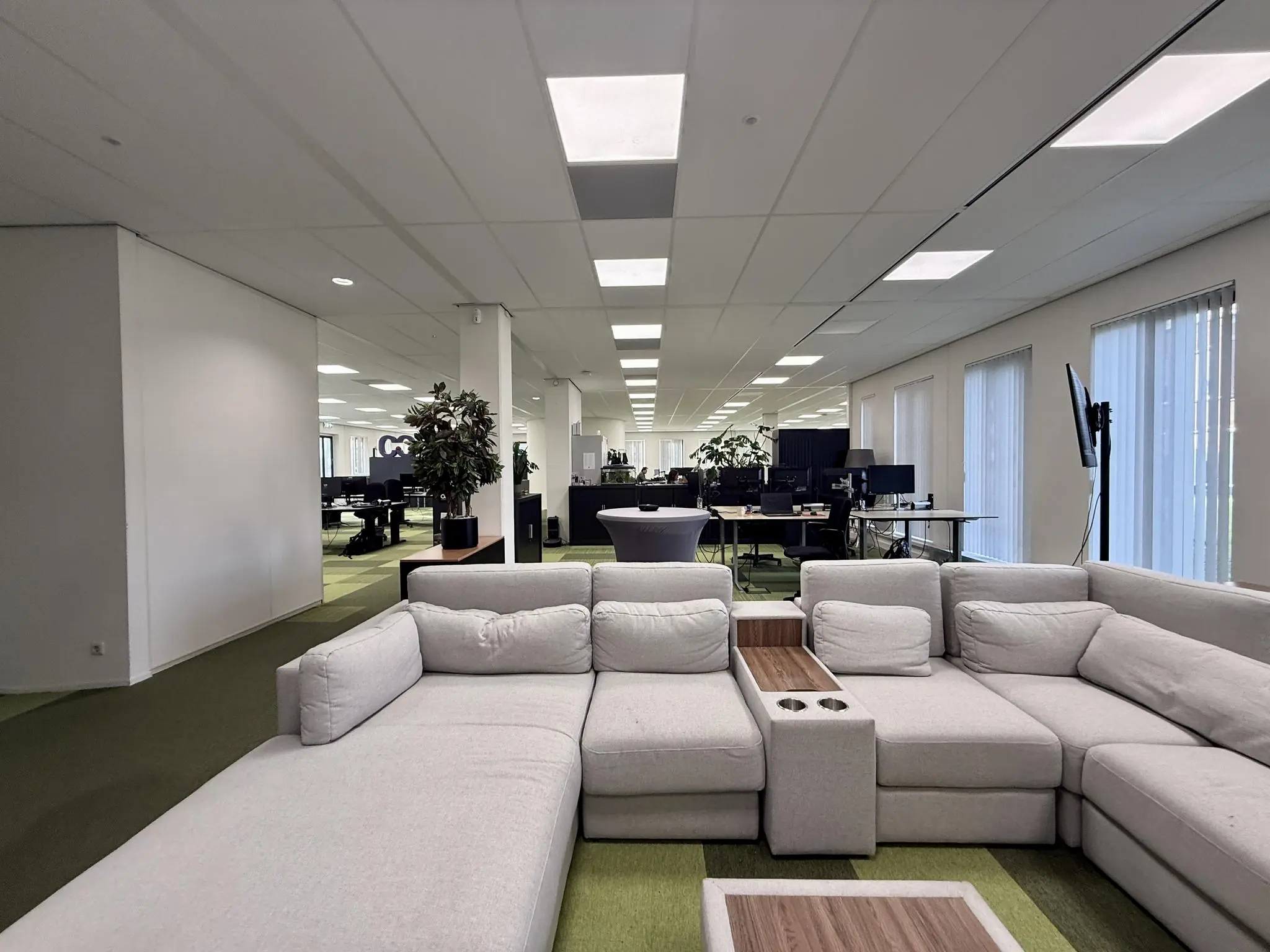 Moderne kantoorruimte aan de Arnhemse Bovenweg met een grote grijze loungebank en open werkplekken op de achtergrond.